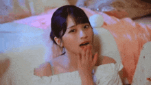 a woman is laying on a bed with a pillow and covering her mouth .