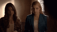 two women are standing next to each other in a dark room
