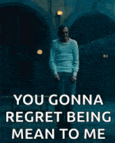 a man is standing in a dark room with the words `` you gonna regret being mean to me '' written on the bottom .