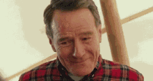 a close up of a man wearing a plaid shirt and smiling .