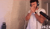 a man wearing headphones and a watch stands in front of a microphone with the number 12623 on the bottom right