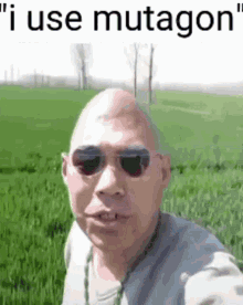 a bald man wearing sunglasses is standing in a field with the words `` i use mutagon '' above him .