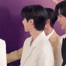 a group of men are standing next to each other and one of them is wearing a white jacket .