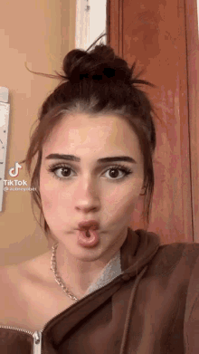 a woman with a bun on her head is making a funny face with her mouth open .
