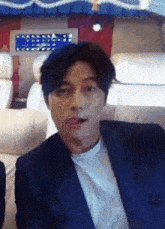 a man in a suit is sitting on a couch and making a funny face