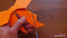 a person is holding a piece of orange paper that says made in animatica