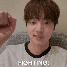 a young man is sitting in a chair with his fist in the air and the word fighting is written below him