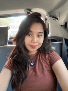 a woman wearing a brown shirt and a blue evil eye necklace