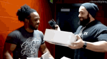 a man wearing a shirt that says girl gun girl rock is holding a box
