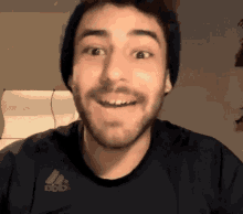 a man wearing a black adidas shirt smiles