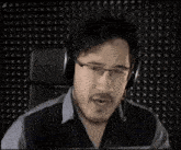 a man wearing headphones is screaming into a microphone in a recording studio .