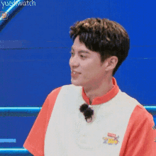 a young man wearing a red and white shirt and sunglasses is sitting in front of a blue background .