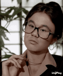 a woman wearing glasses and hoop earrings looks at the camera with imgplay written below her