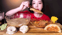 a woman in a red shirt is eating a large bowl of food