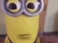 a close up of a minion wearing goggles and making a surprised face .