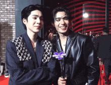 two men are standing next to each other on a red carpet and one of them is wearing a jacket that says starlight news on it