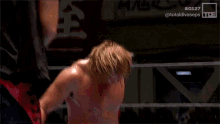 a shirtless wrestler is waving his hand in front of a sign that says bg127