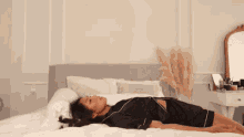 a woman is laying on her stomach on a bed with her head on the pillow .
