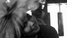 a black and white photo of a woman laying down with her head down .