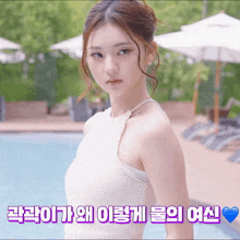 a woman in a white dress is standing in front of a pool with umbrellas
