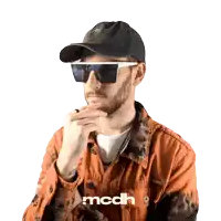 a man wearing sunglasses and a hat with the letters mcdh on the bottom