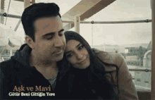 a man and a woman are sitting on a ferris wheel with the words aşk ve mavi written on the bottom