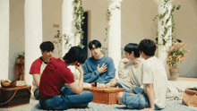 a group of young men are sitting around a picnic basket on a patio
