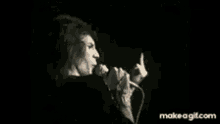 a woman singing into a microphone with the website makeagif.com in the corner