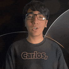 a young man wearing glasses and a shirt that says carlos on it