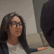 a woman wearing glasses is sitting on a couch with a man