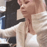 a woman with pink hair is wearing a white sweater and a white tank top