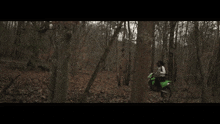 a person riding a green motorcycle through a forest