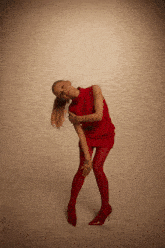 a woman in a red dress and red tights is posing for a photo