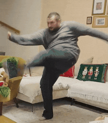 a man is jumping in the air in front of a couch with a nutcracker pillow