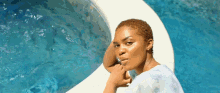 a woman is sitting on the edge of a pool