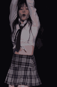a woman in a white crop top and plaid skirt is dancing on a stage