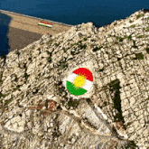 an aerial view of a rocky hillside with a circle painted in the colors of the kurdish flag