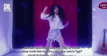 a woman is dancing in front of a snl logo