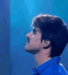 a man with a mustache is wearing a blue shirt .