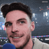 a man with a beard is smiling in front of a blue microphone with the word canirove in the upper right corner