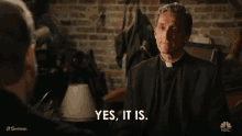 a man in a suit says yes it is in front of a brick wall