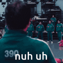 a man wearing a green jacket with the number 390 on it stands in front of a group of people .