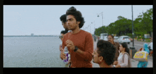 a man in an orange sweater is holding a bottle of water in his hand