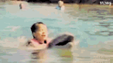 a little girl is swimming in a pool with a dolphin in the background .