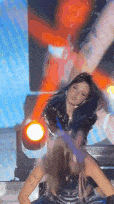 a woman with blue hair is dancing on a stage in front of a red light .