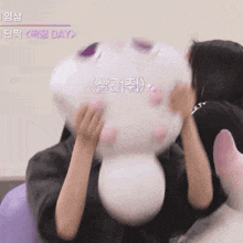 a woman is holding a stuffed animal in front of her face while another woman looks on ..