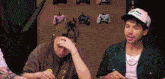 a man and a woman are sitting in front of a wall with controllers on it