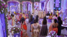 a group of people are standing in a room with flowers