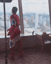 a man in a superhero costume looks out a window at the city