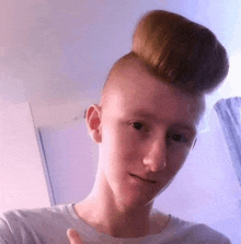 a young man with a big bun on his head is taking a selfie .